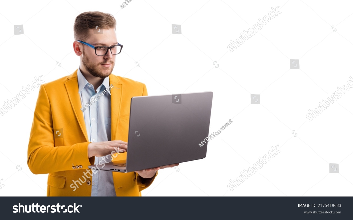 Concentrated serious businessman working online with copy space in white studio. Focused young professional entrepreneur web surfing on modern wireless laptop. #2175419633