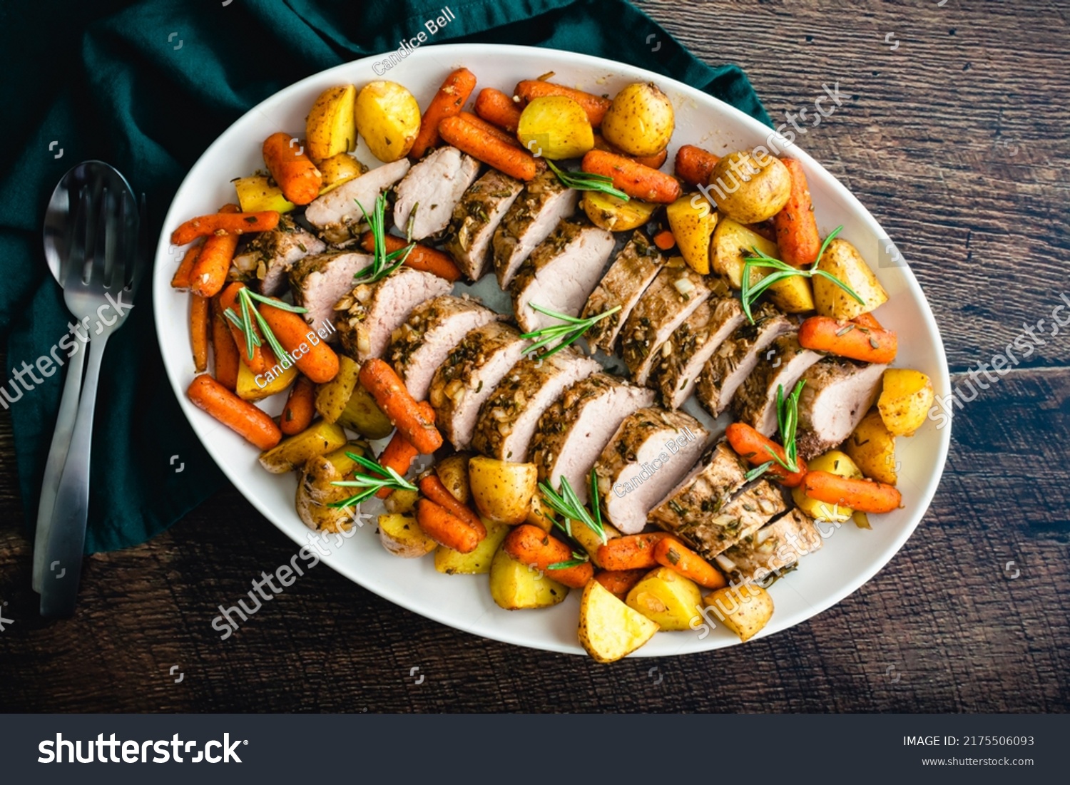Roast Pork Tenderloin with Potatoes and Baby Carrots: Sliced pork medallions surrounded with vegetables on a platter #2175506093