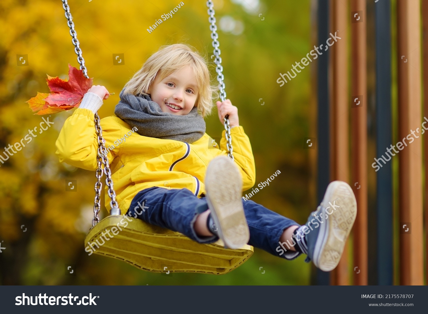 Little boy having fun on a swing on the playground in public park on autumn day. Happy child enjoy swinging. Active outdoors leisure for child in city #2175578707