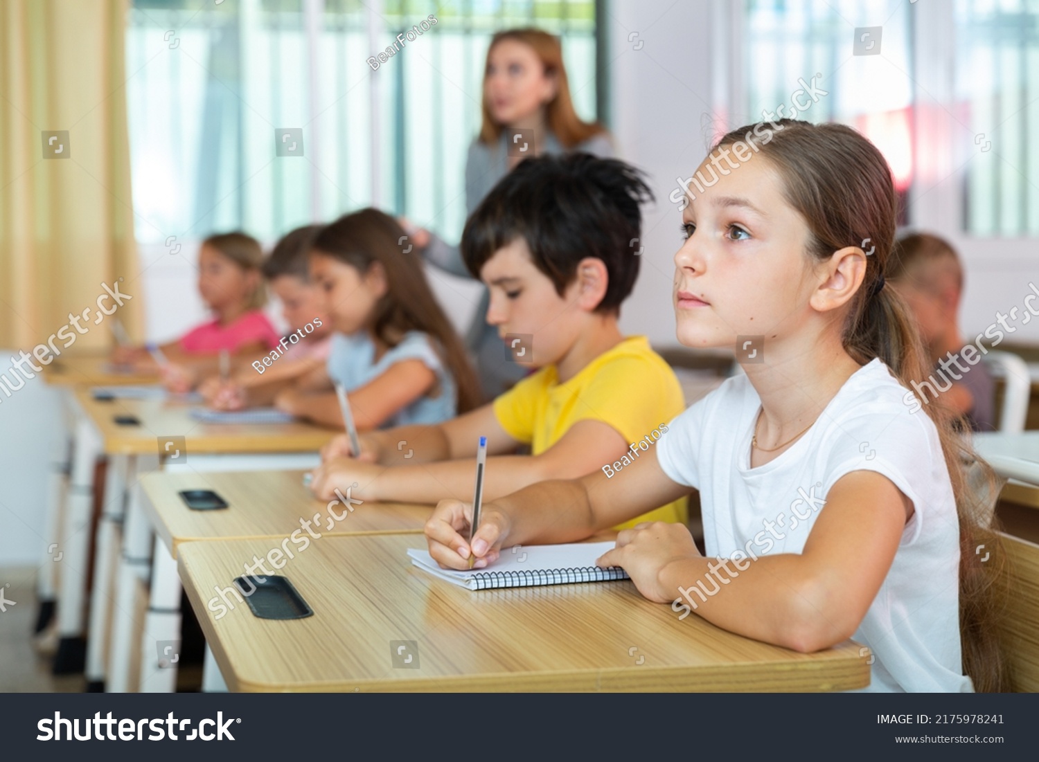 Schoolgirl sitting in classroom during lesson in elementary school. High quality photo #2175978241