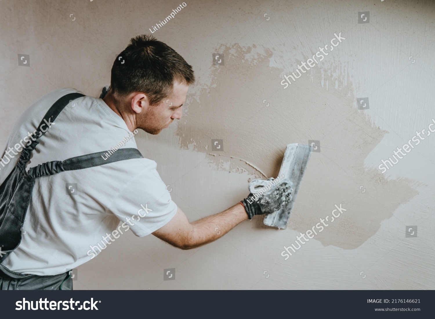 Male builder in work overalls plastering a wall using a construction trowel. Horizontal panorama banner with blank space for text. #2176146621