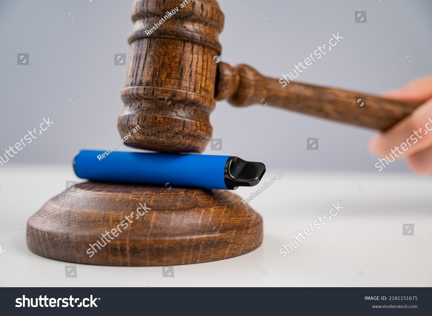 Judge hammering disposable vape with referee's gavel on white table.  #2181151675