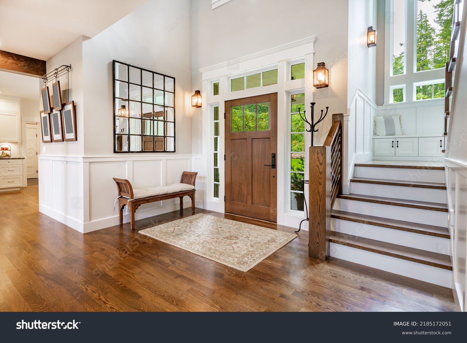 front entry foyer of a luxurious home rich wood tones staircase bench with a welcoming feel #2185172051