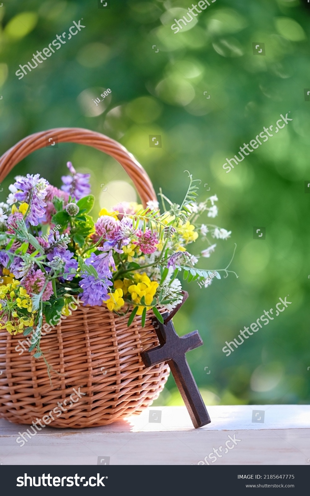 Christian cross and meadow flowers in wicker basket on table, natural background. Herbal consecration - traditional customs of August 15, day of the Assumption of Mary, know as Divine Mother of Herbs #2185647775