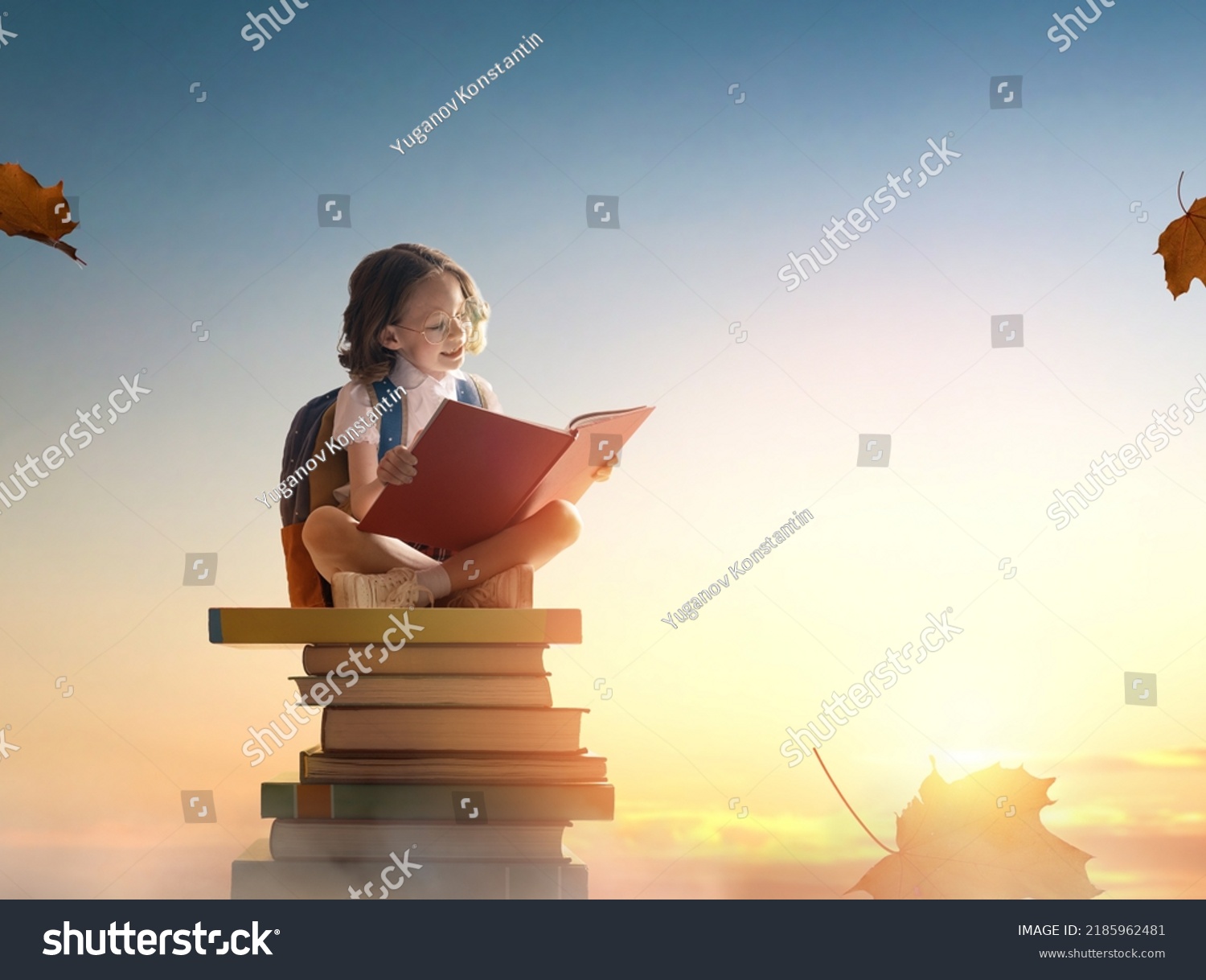 Back to school! Happy cute industrious child sitting on the tower of books on background of sunset sky. Concept of education and reading. The development of the imagination. #2185962481