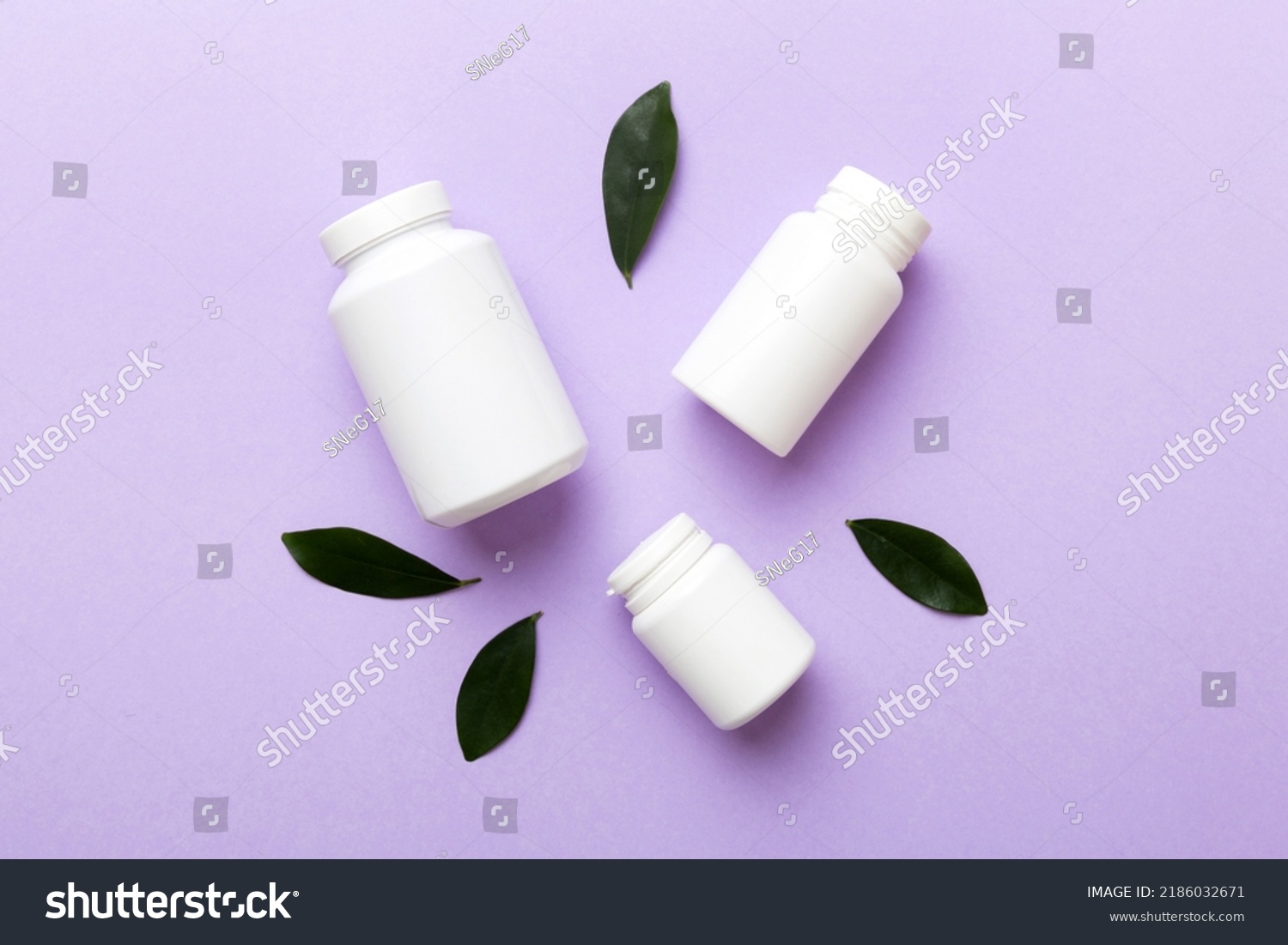 supplement pills with medicine bottle health care and medical top view. Vitamin tablets. Top view mockup bottle for pills and vitamins with green leaves, natural organic bio supplement, copy space. #2186032671