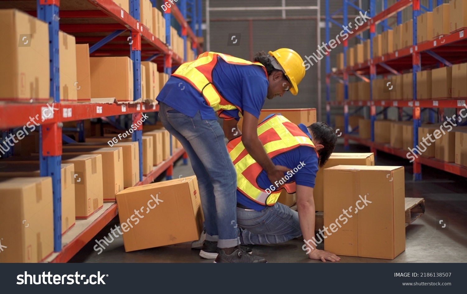 Careless Asian warehouse worker lifting a heavy cardboard box to the shelf then some of the box falling and hit by accident and his friend run to safe or help him. Safety instruction in working area. #2186138507