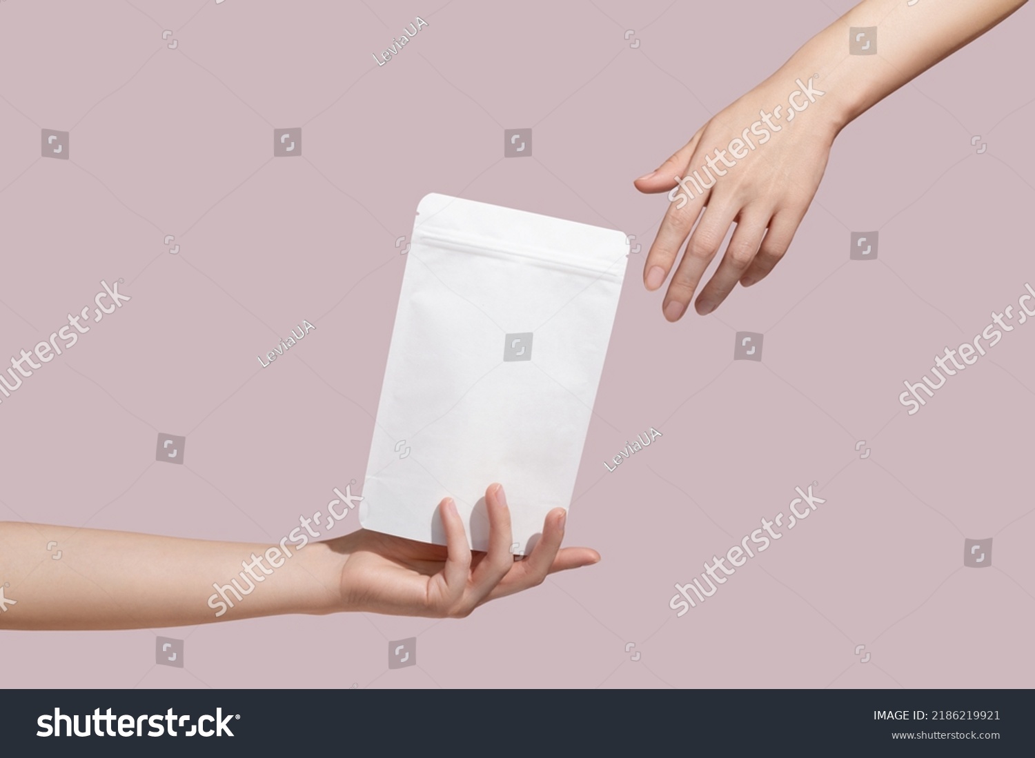 Female hand holds white cardboard packaging for tea, coffee, snack on pink background. Branding and packaging mockup. High quality photo #2186219921