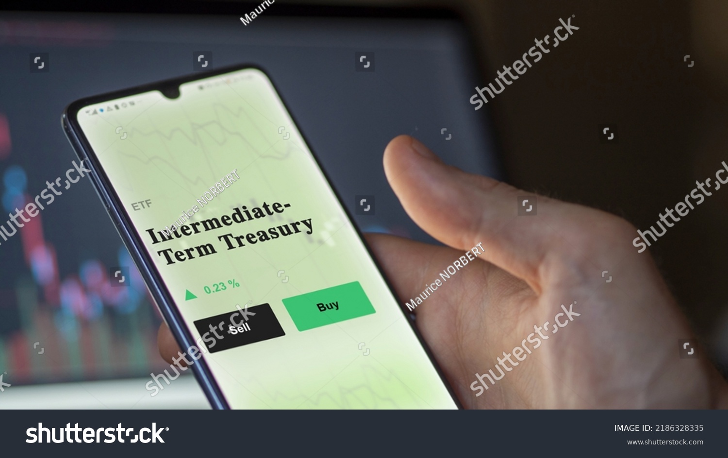 An investor's analyzing the intermediate-term treasury etf fund on a screen. A phone shows the prices of Intermediate-Term Treasury #2186328335