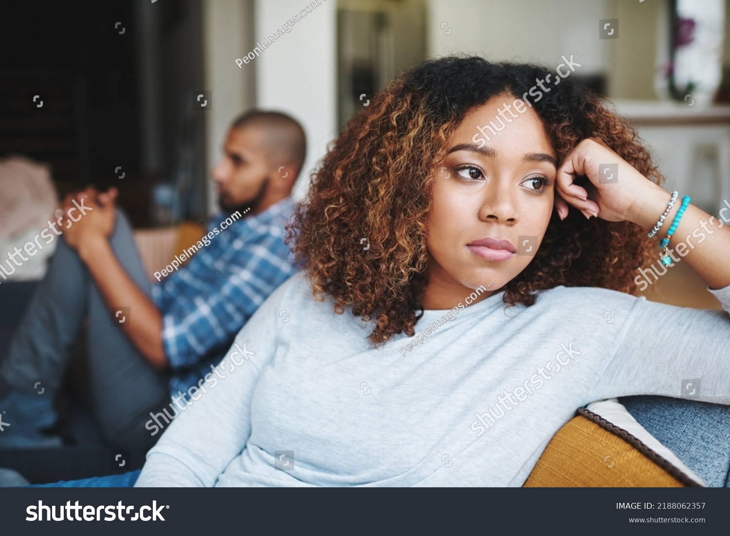Unhappy couple and sad woman upset after argument or conflict with her man on home sofa. Angry girlfriend or female thinking about disagreement or ignoring partner, tired of relationship problems. #2188062357