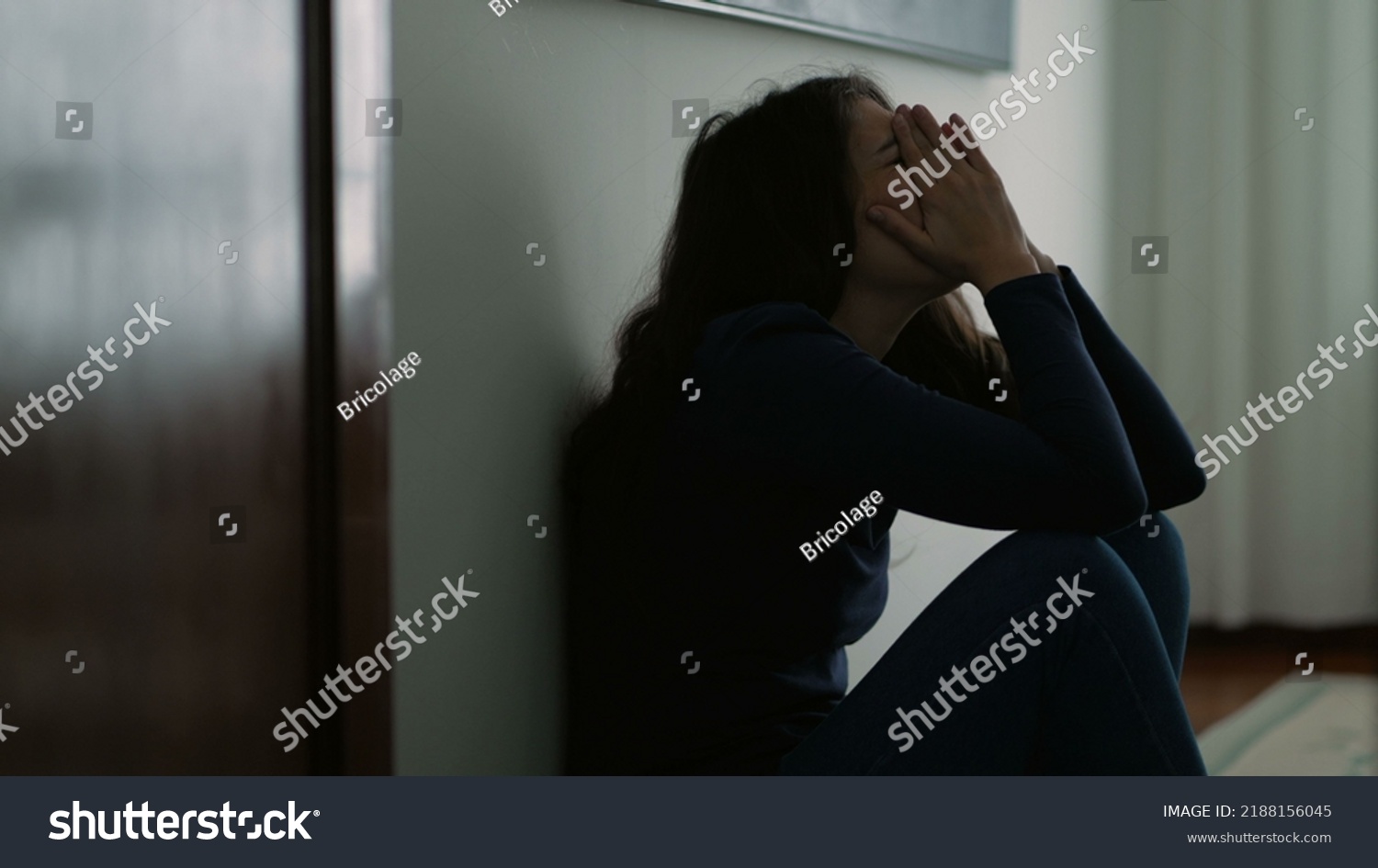 Woman feeling emotional pain sitting on floor home being desperate covering face with shame #2188156045