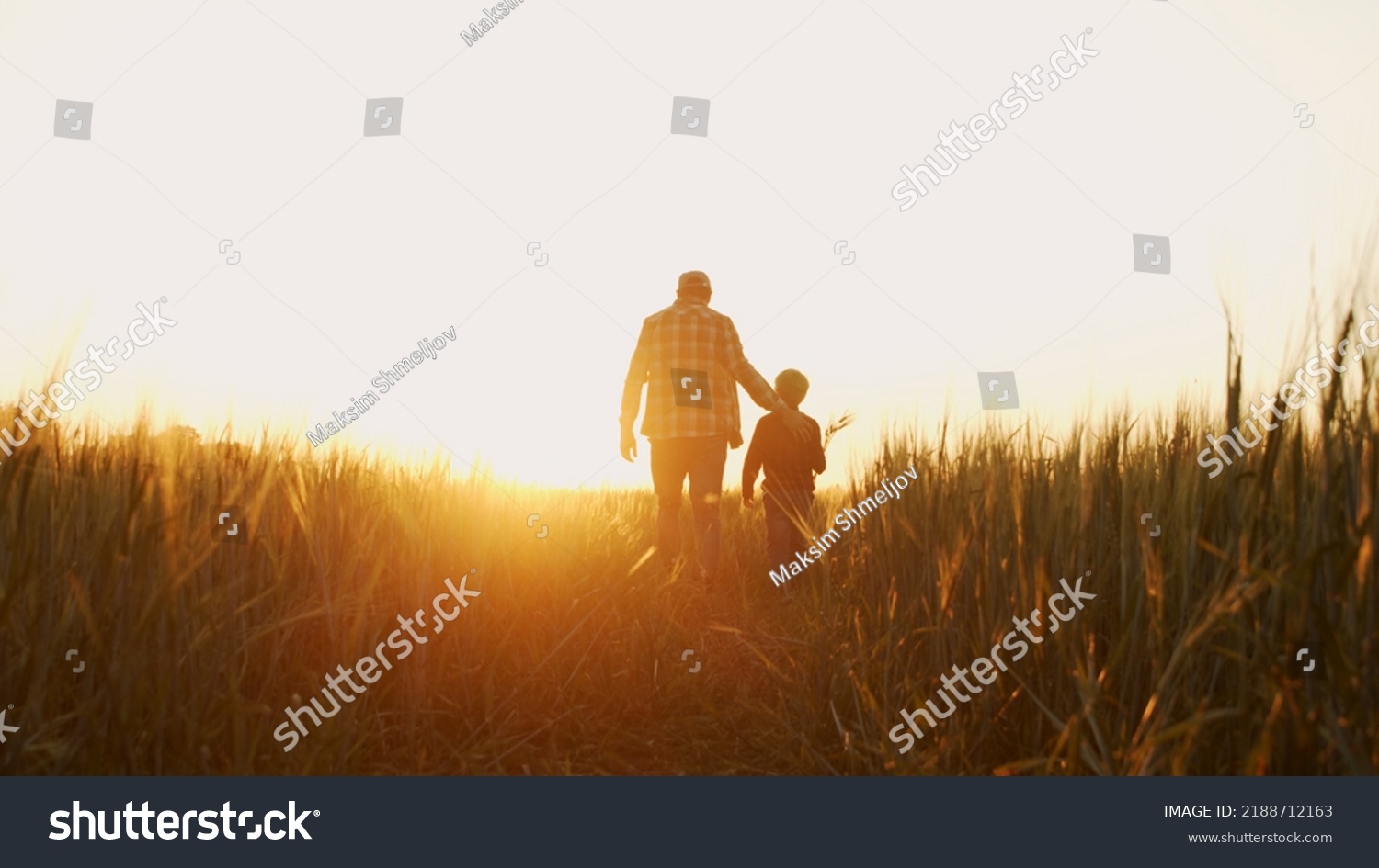 Farmer and his son in front of a sunset agricultural landscape. Man and a boy in a countryside field. Fatherhood, country life, farming and country lifestyle. #2188712163