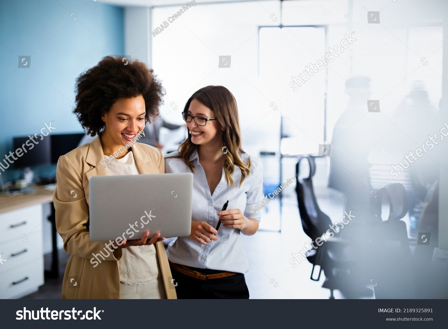 Happy multiethnic business women working together online on a laptop in corporate office. #2189325891