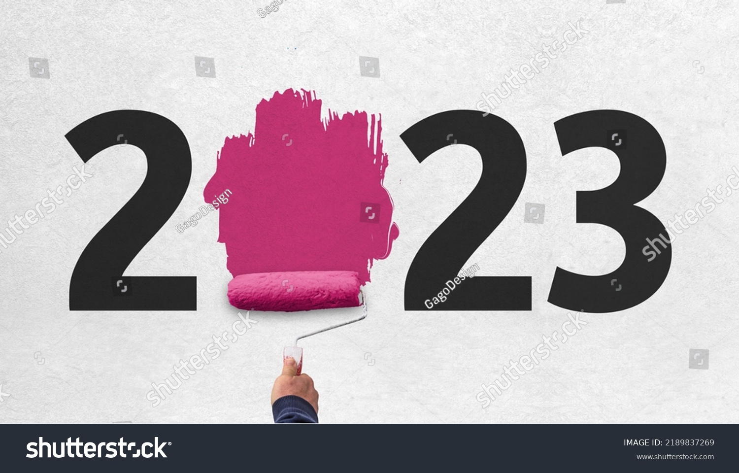 hand holds paint roller and painting 2023 year on wall. happy new year 2023  #2189837269