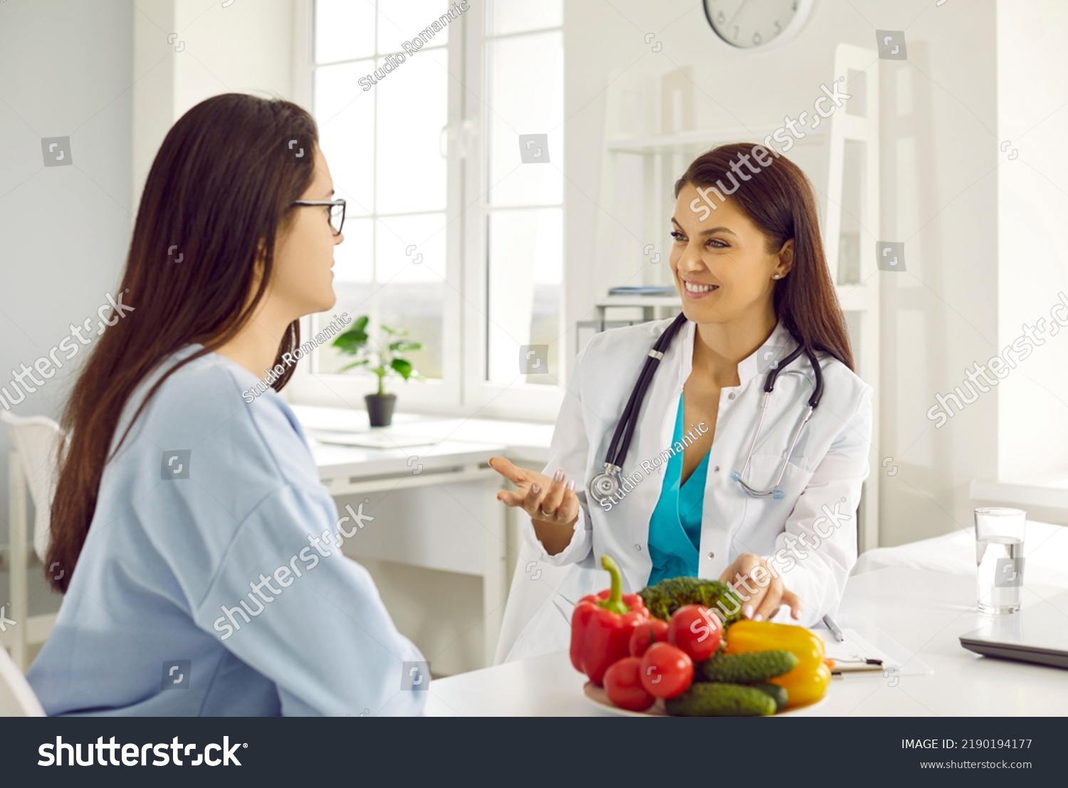 Friendly female nutritionist advises woman on diet plan and talk about benefits of raw vegetables. Doctor consults young female patient in hospital office. Concept of healthy eating and food science #2190194177