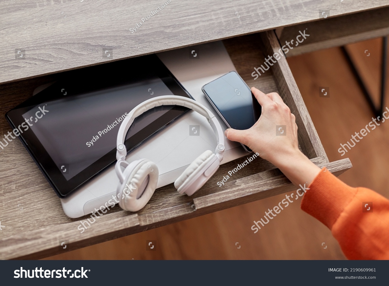 digital detox and technology concept - close up of hand with smartphone and different gadgets in desk drawer at home #2190609961