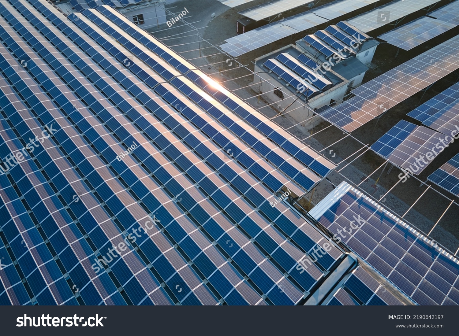 Aerial view of solar power plant with blue photovoltaic panels mounted on industrial building roof for producing green ecological electricity. Production of sustainable energy concept #2190642197