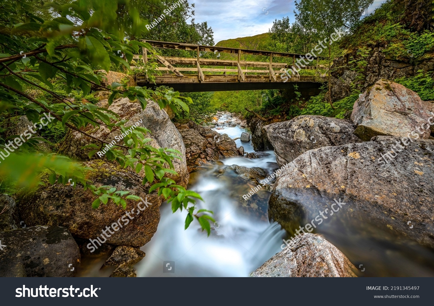 Wooden bridge over the forest river. River bridge. Bridge over river rocks. River bridge view #2191345497
