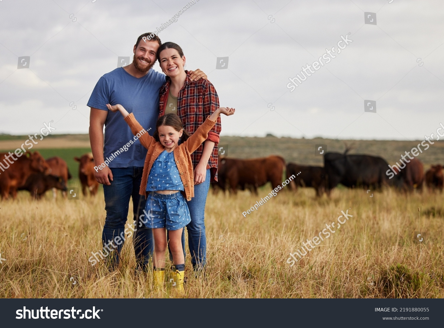 Happy family standing on a farm, cow in background and with a vision for growth in industry portrait. Countryside couple, people or farmer in a field of grass, cattle and free range livestock #2191880055