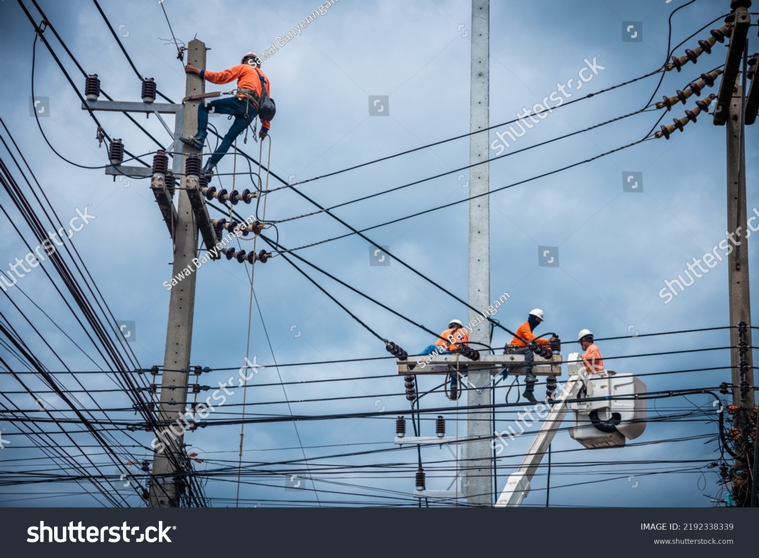 Asian electricians are climbing on electric poles to install and repair power lines. #2192338339