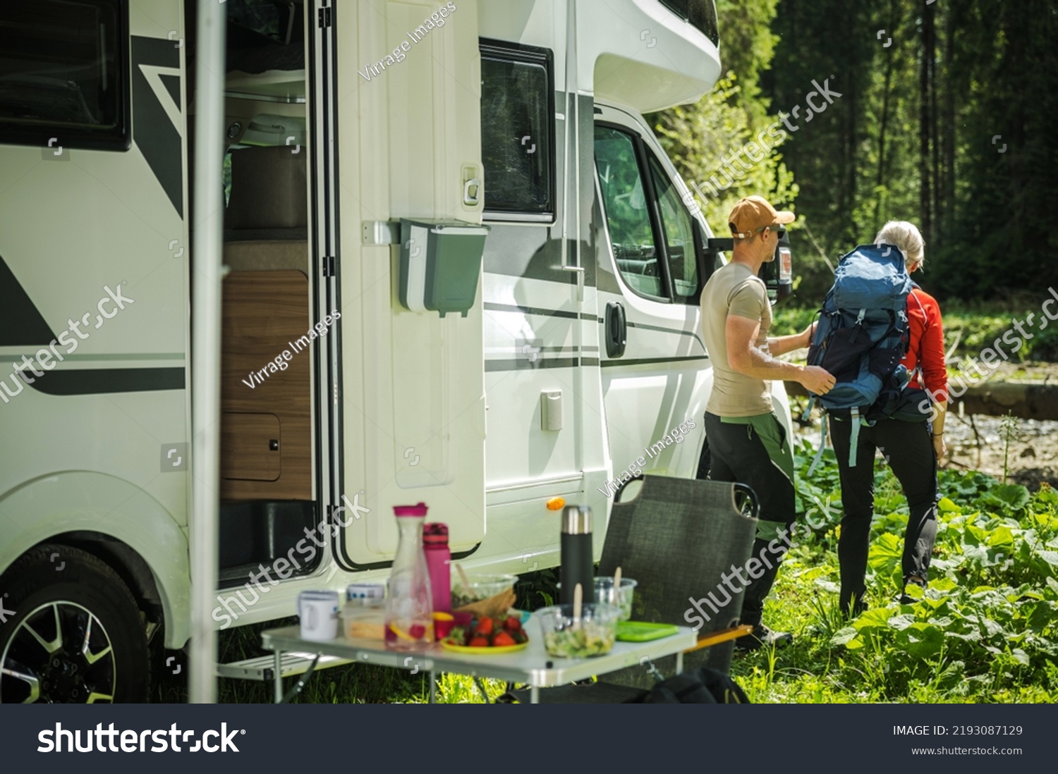 Caucasian Camping Couple Next to Their Class C Motor Home. Preparing For a Hike. Recreational Vehicles Theme. #2193087129