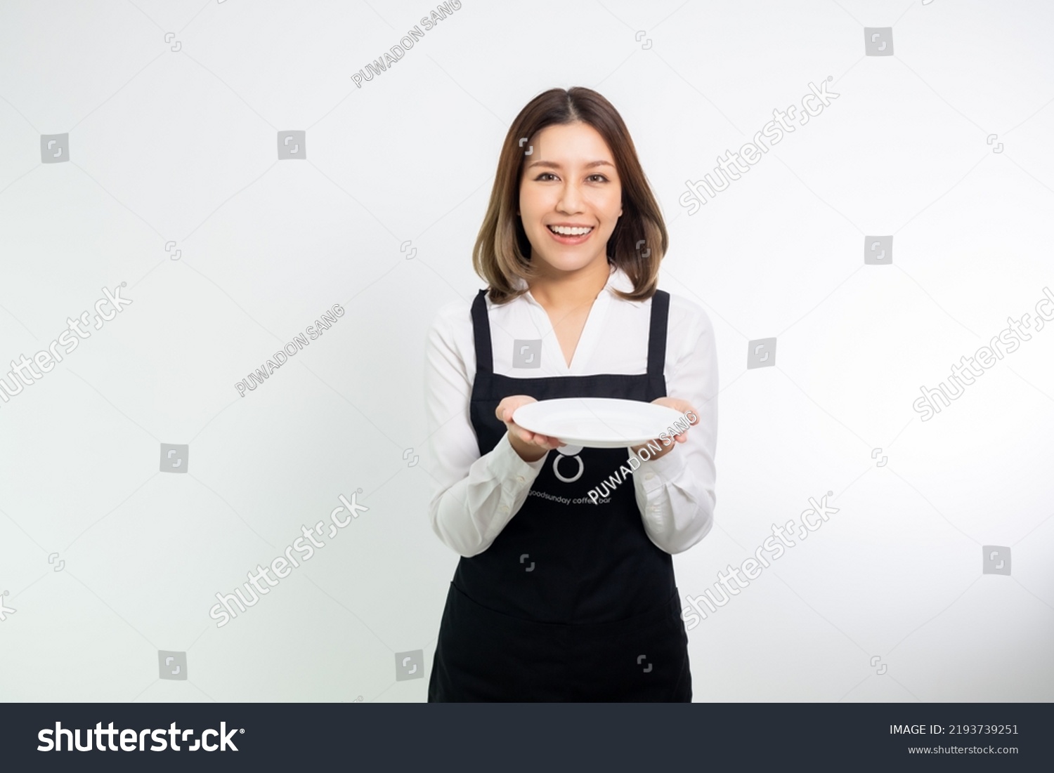 Asian woman in apron holding empty white plate or dish. #2193739251