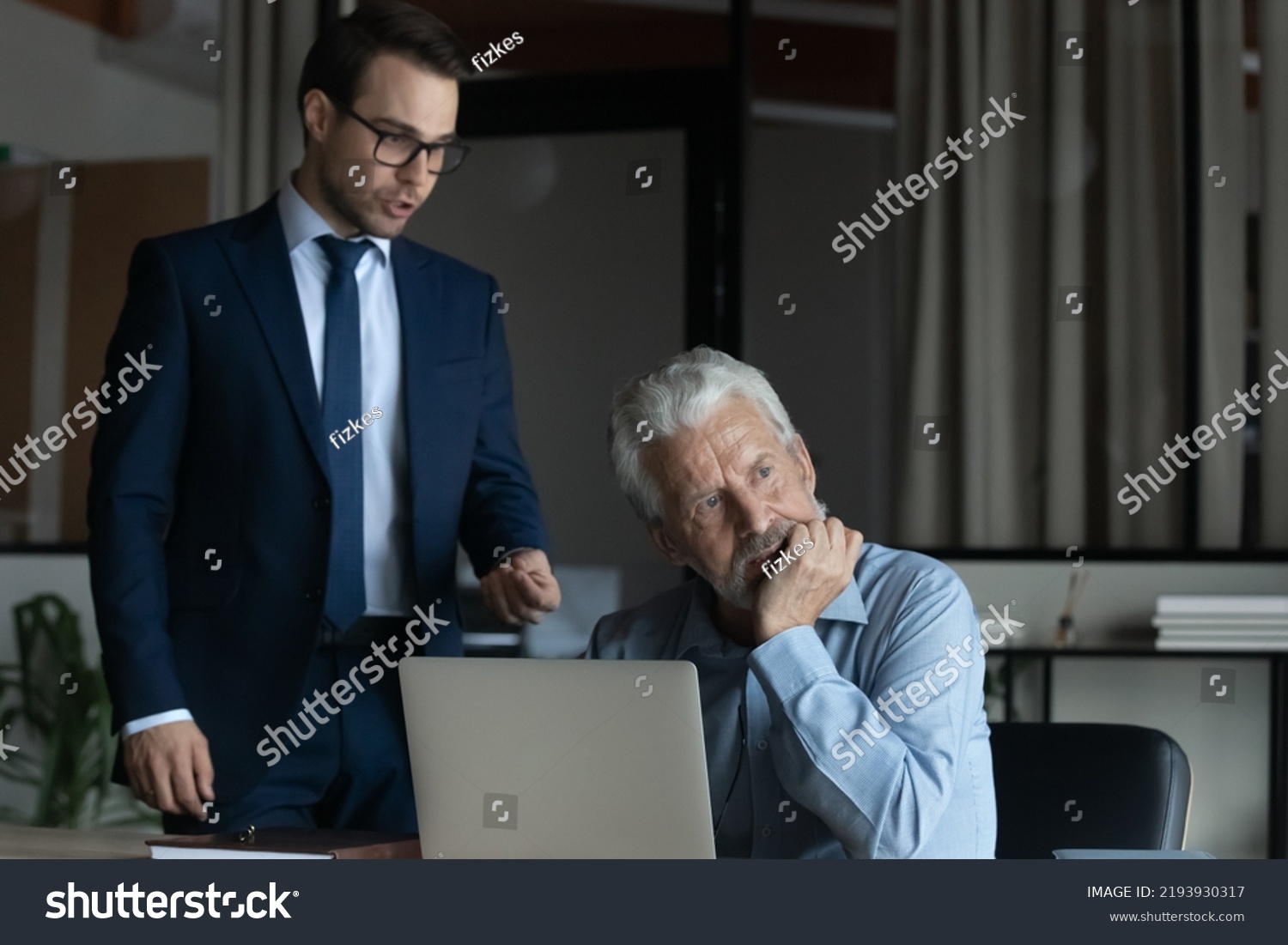 Angry businesswoman executive wearing glasses blaming scolding mature employee for business failure, bad work results, irritated dissatisfied boss lecturing upset senior worker, conflict concept #2193930317