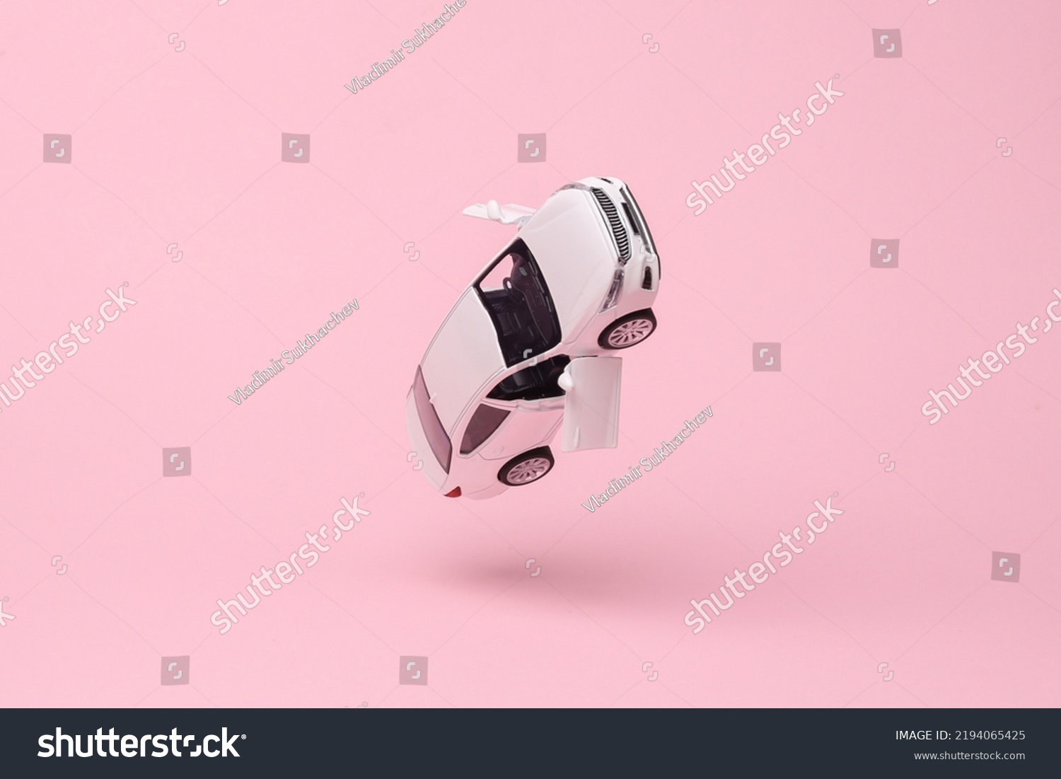Miniature car model flying in antigravity on pink background with shadow. Levitation object in the air. Creative minimal layout #2194065425
