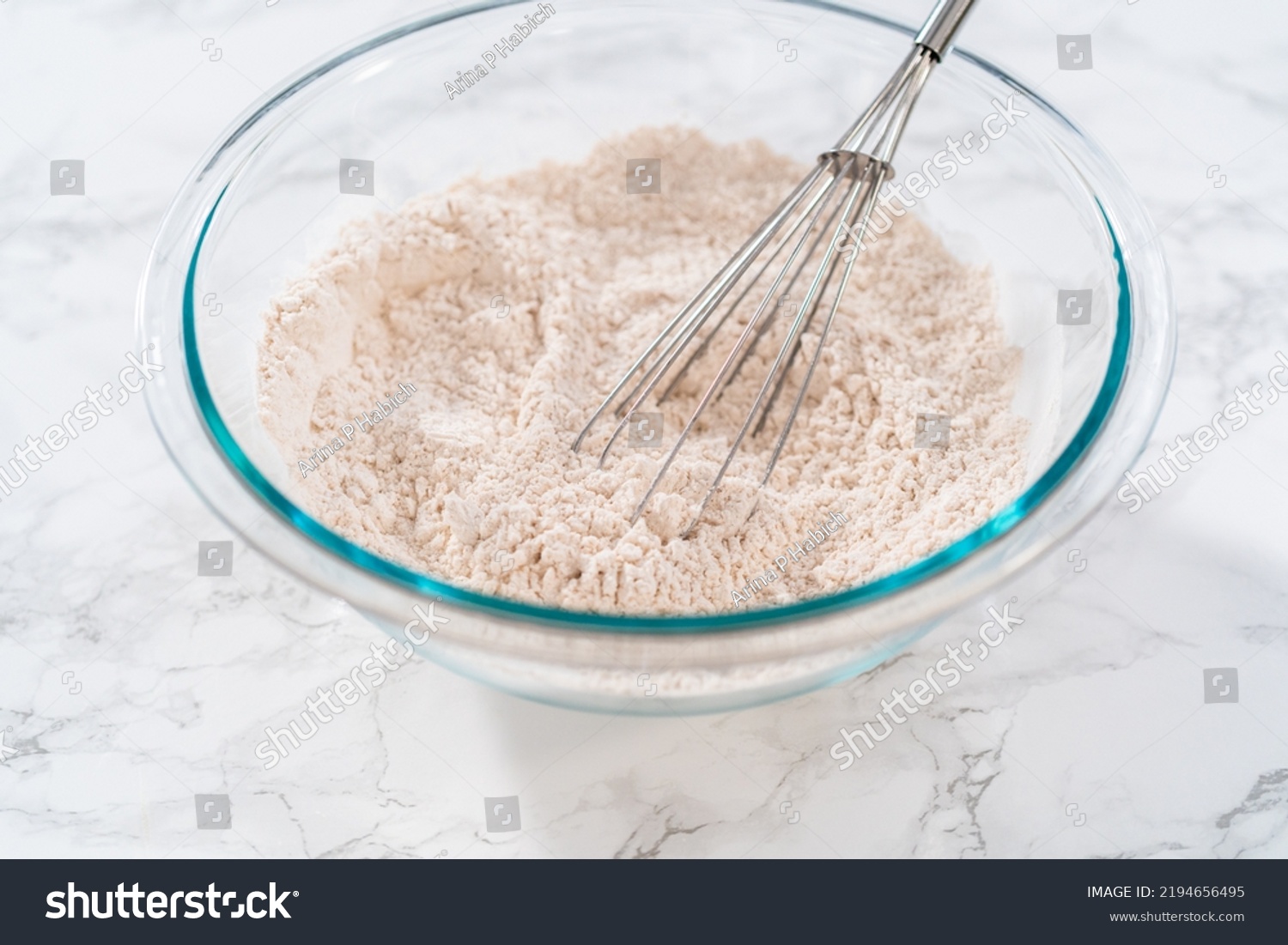 Mixing dry ingredients in a large glass mixing bowl to bake eggnog cookies with a chocolate gingerbread man. #2194656495