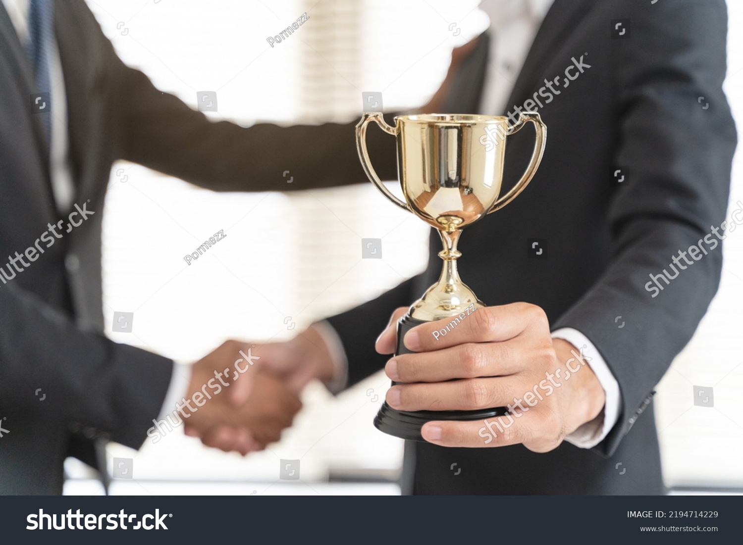 The hands of an employee receiving a golden cup reward from the company manager represent his performance in his career job reward. #2194714229