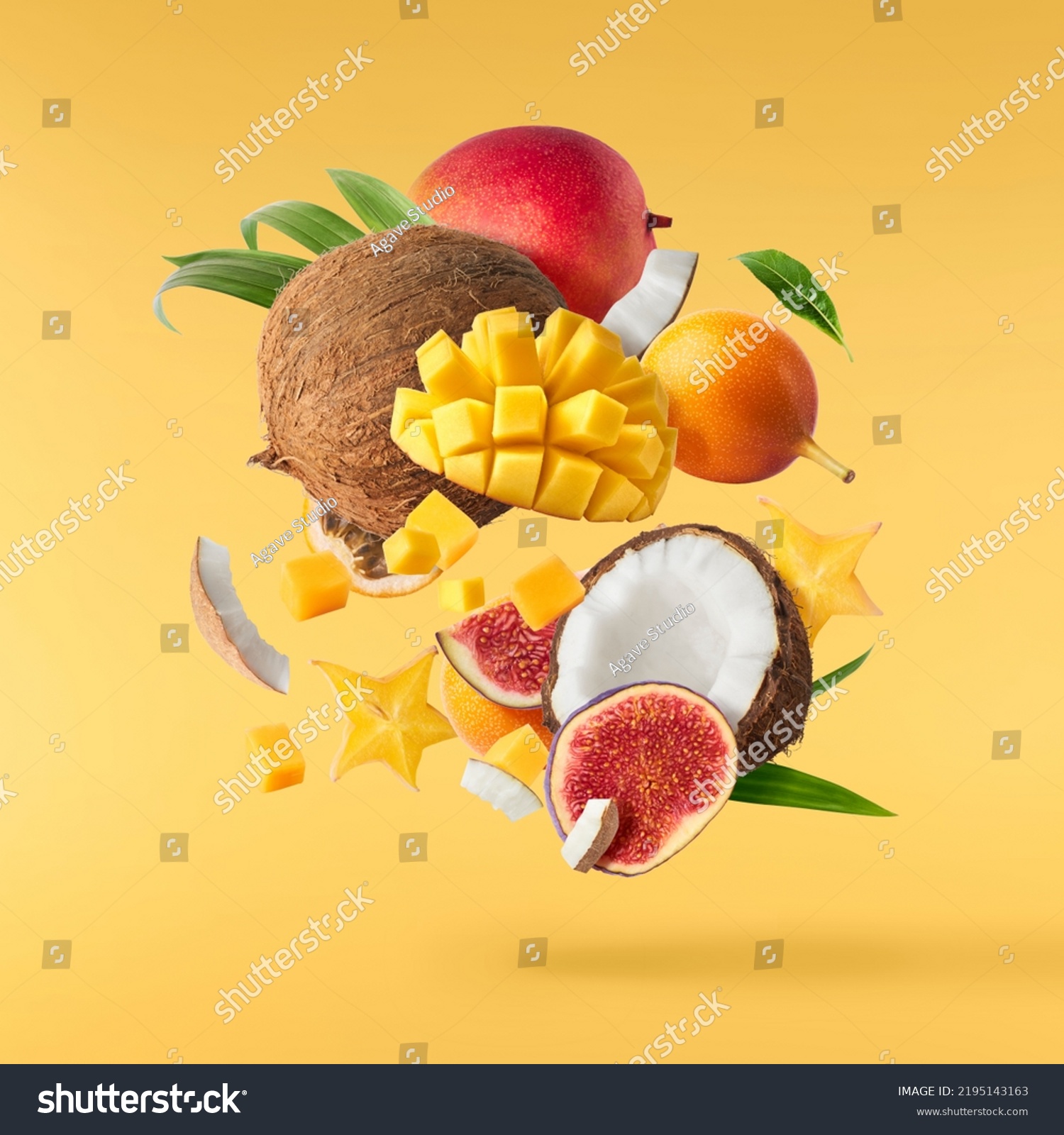 Exotic fruit mix, coconuts, mango, fig, passiflora, carambola falling in te air isolated on yellow background. Food levitation, zero gravity conception. High resolution image #2195143163