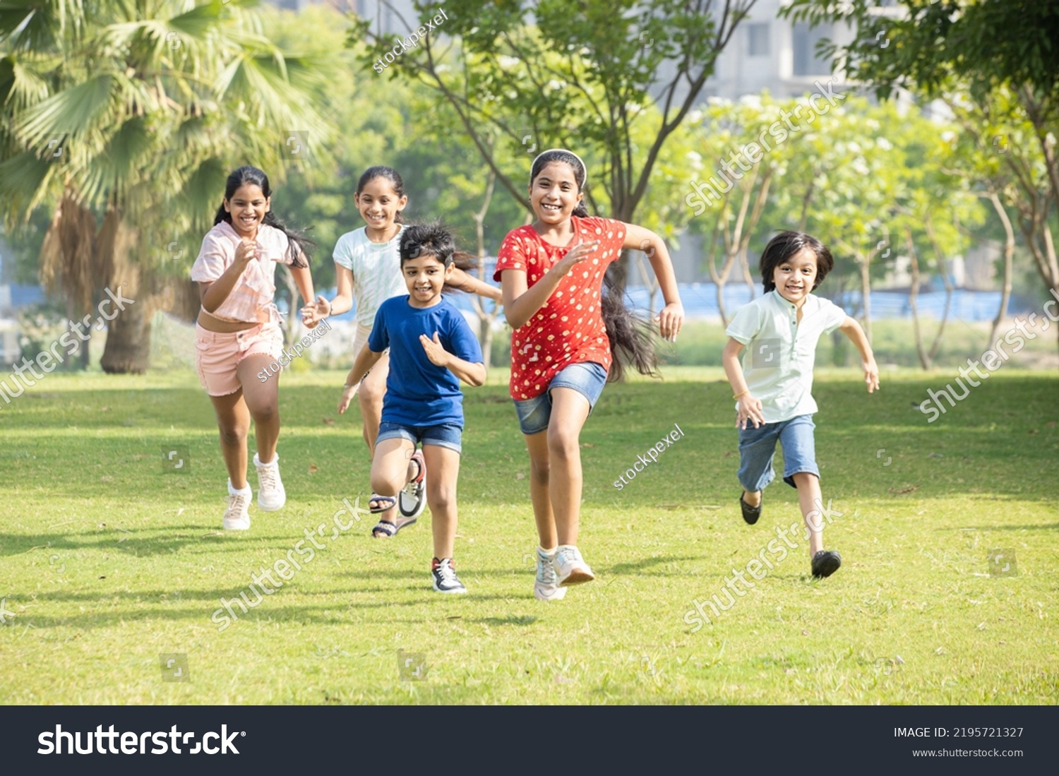 Group of happy playful Indian children running outdoors in spring park. Asian kids Playing in garden. Summer holidays.  #2195721327