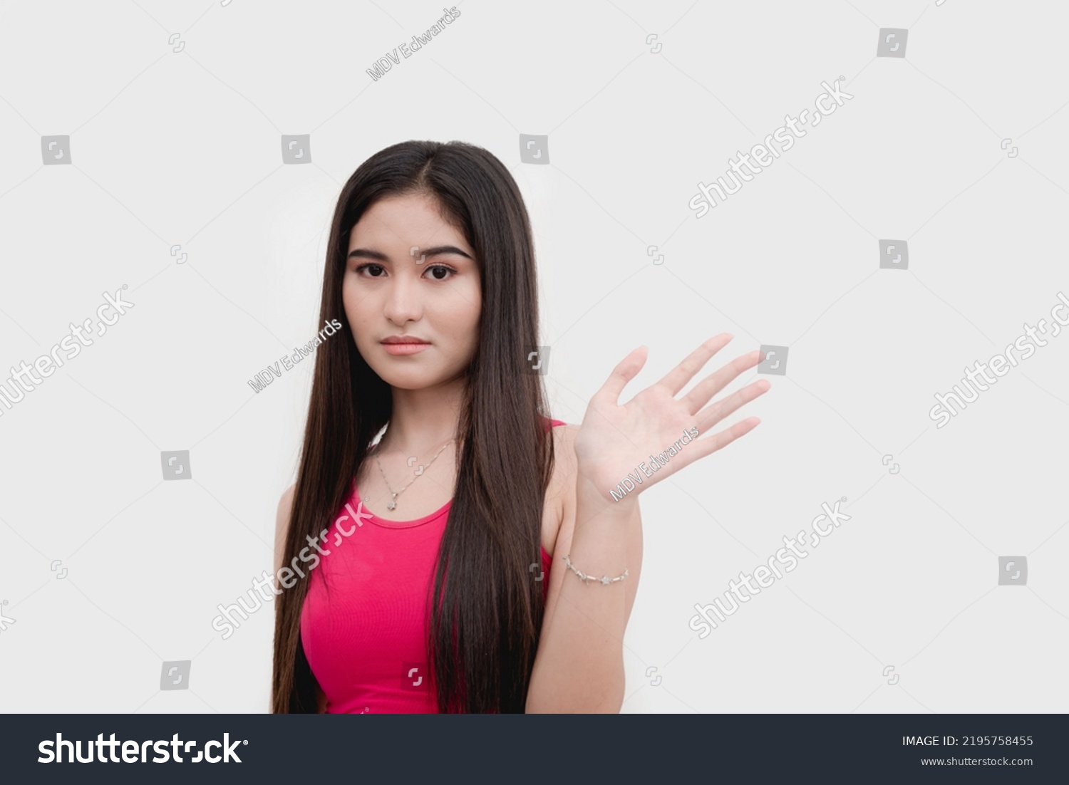 A young uneasy asian woman waving someone off expressing disinterest or apprehensiveness. Isolated on a white backdrop. #2195758455