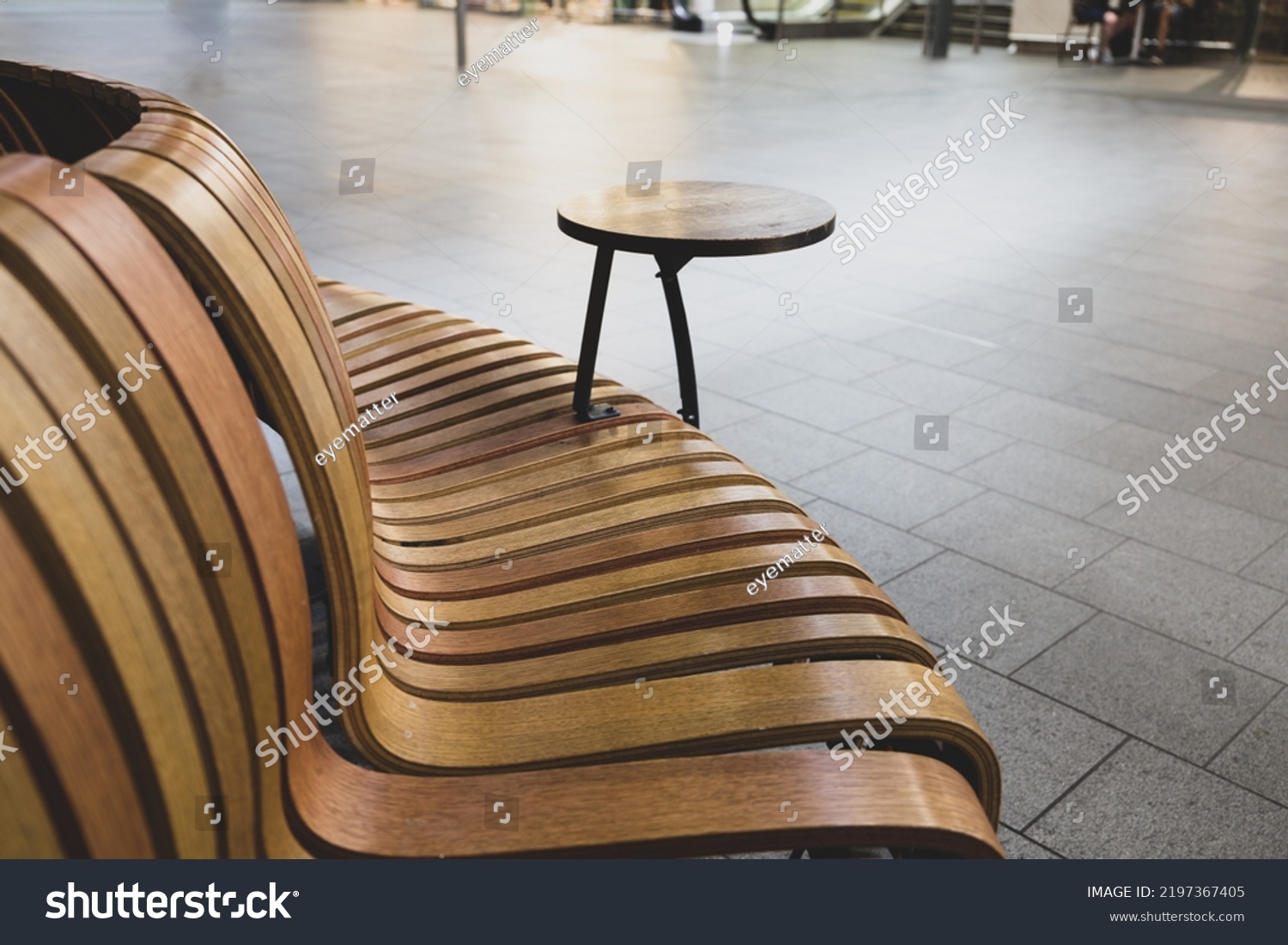Elegant curved contemporary wooden seating area with built in table on a modern railway station concourse #2197367405