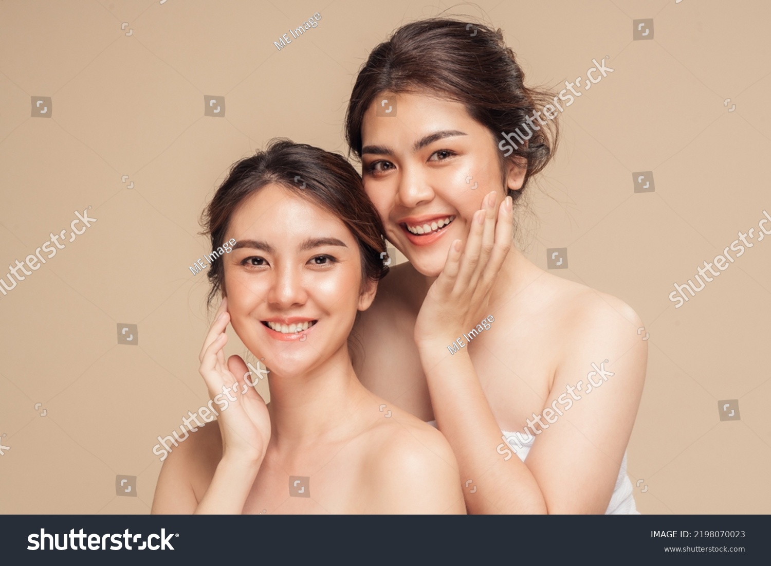 Two Asian woman with beauty face touching healthy skin care. Beautiful female models happy smiling with perfect face skin and natural makeup on beige background. Spa skin care concept. #2198070023