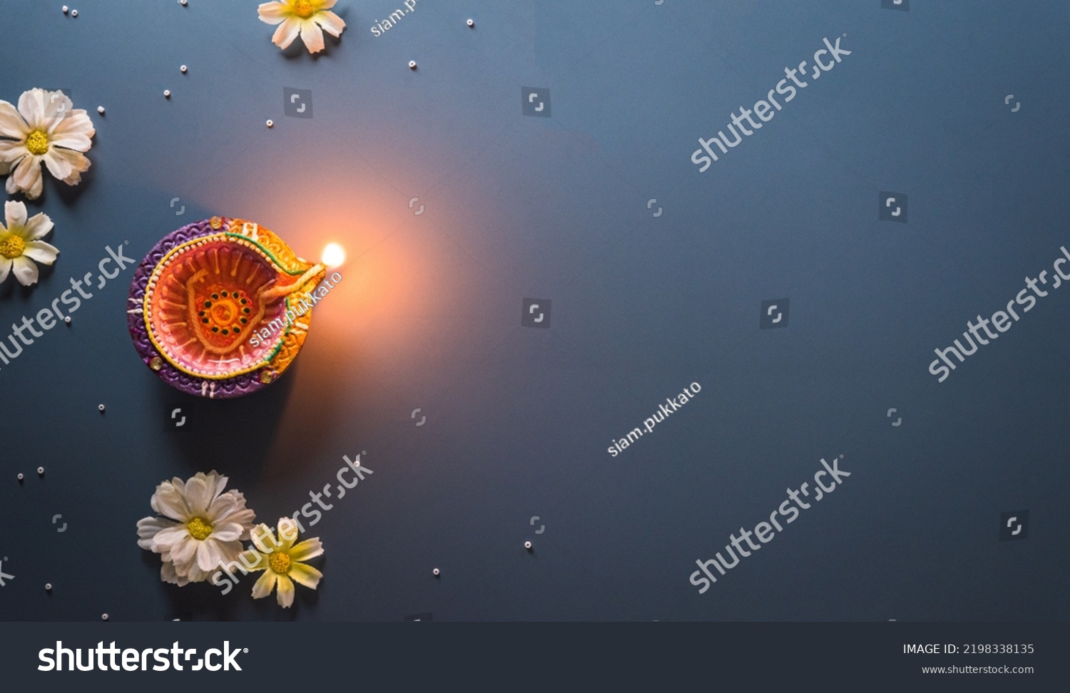 Happy Diwali - Clay Diya lamps lit during Diwali, Hindu festival of lights celebration. Colorful traditional oil lamp diya on blue background #2198338135