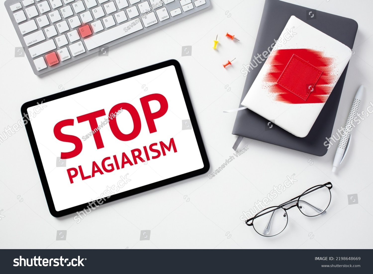 Stop plagiarism concept. Flat lay digital tablet with text STOP PLAGIARISM on screen, keyboard with lighted keys control c, paper notebooks, glasses on white desk. #2198648669