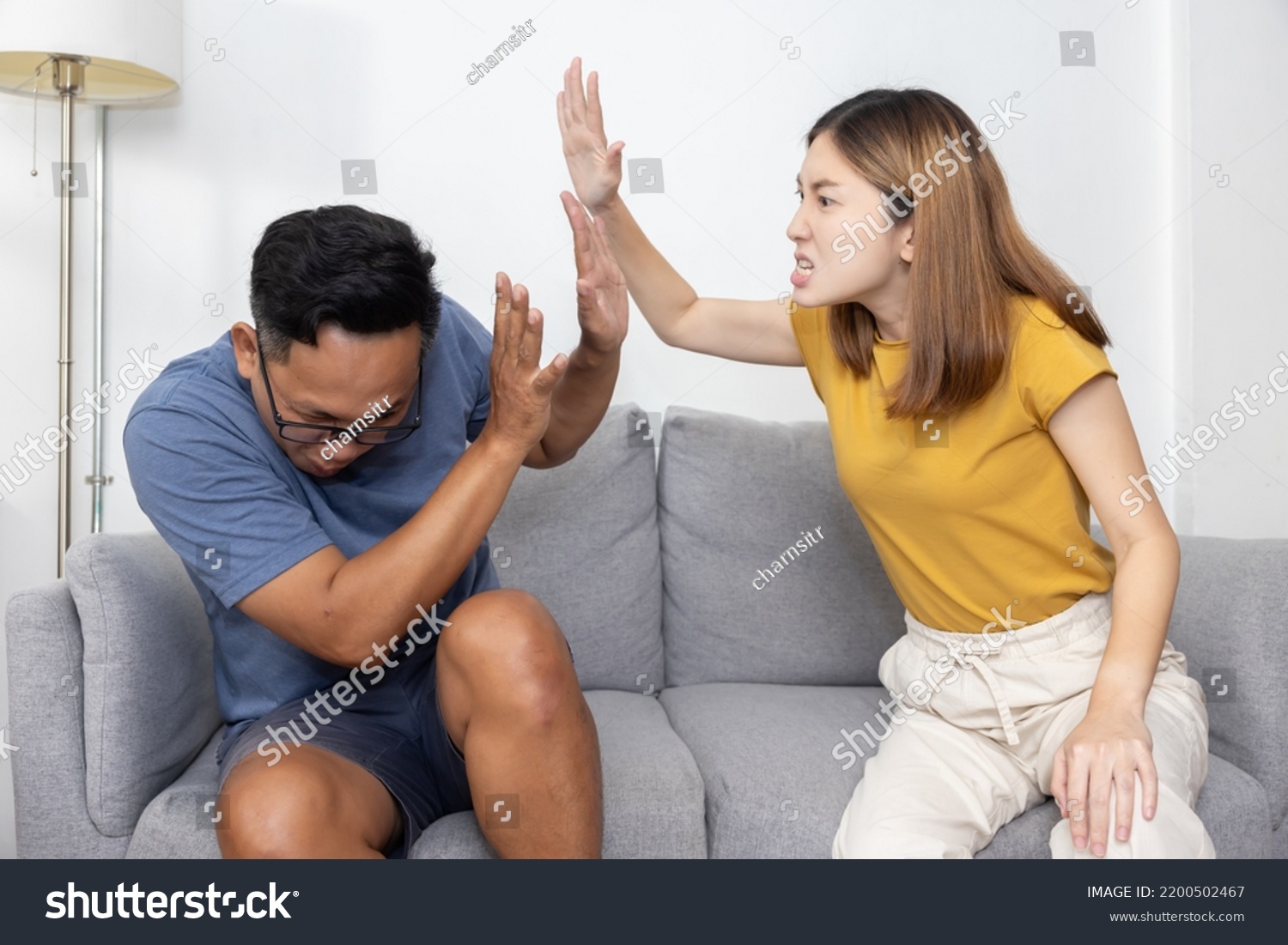 Asian Wife Hit Her Cheating Husband on Couch at Home  for  a Couple Fighting and Domestic Violence Concept #2200502467