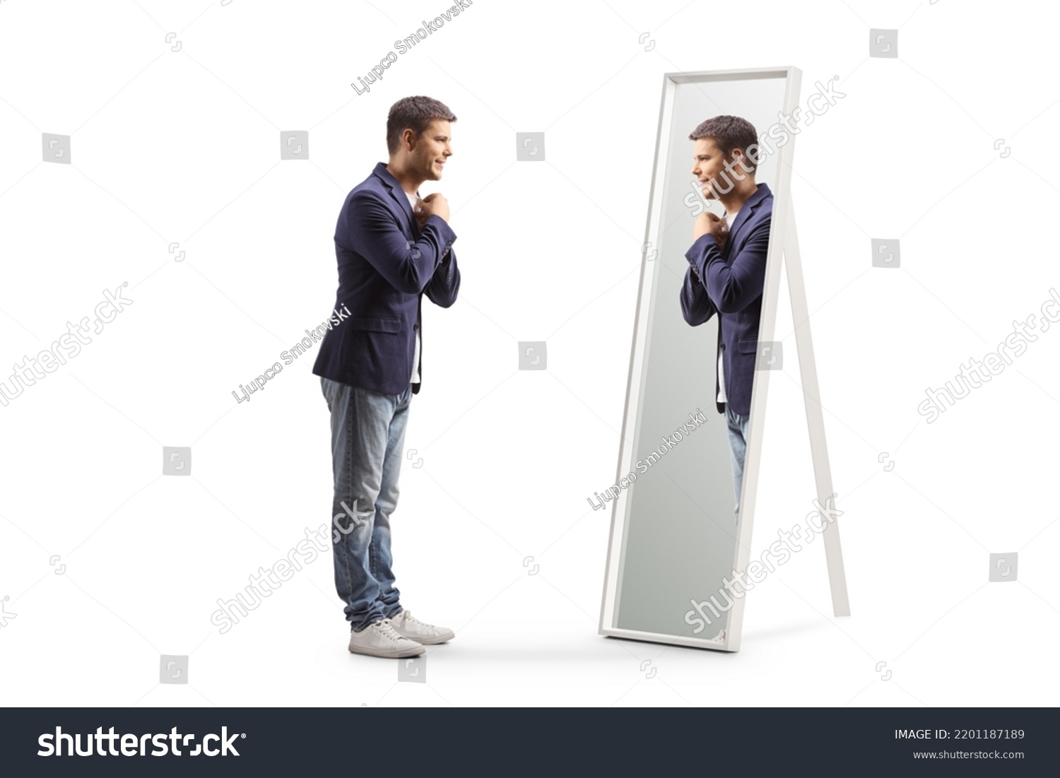 Full length profile shot of a young man getting ready and looking at a mirror isolated on white background #2201187189