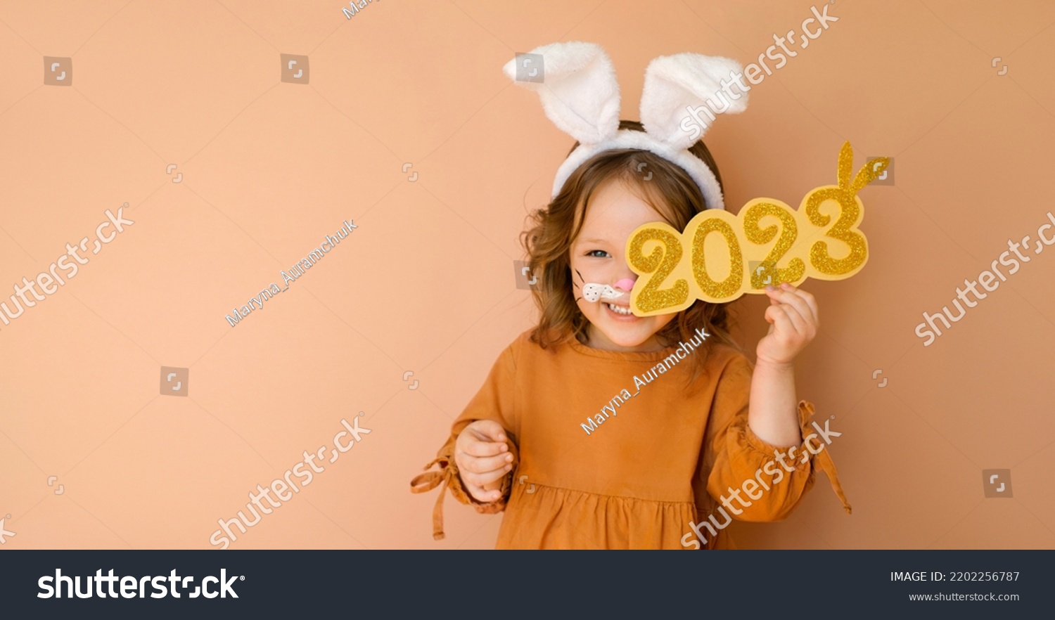 A funny laughing child in the guise of a rabbit closes his eye with the numbers 2023. The year according to the zodiac sign of the Eastern calendar. Christmas Greeting poster #2202256787