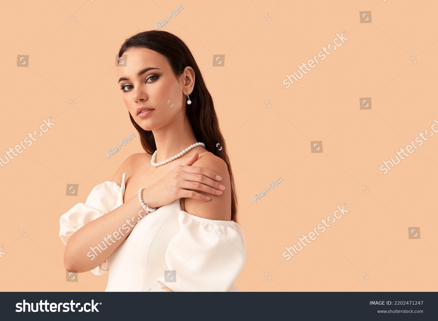 Beautiful young woman with stylish pearl jewelry on beige background #2202471247
