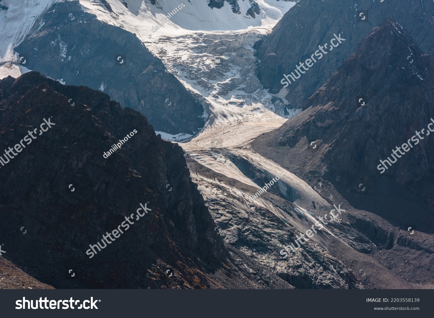 Atmospheric landscape with large snow mountain range in sunny day. Glacier and icefall in bright sun among sharp rocks. Awesome mountain view to high snowy mountains. Sunlit beautiful icefall close-up #2203558139