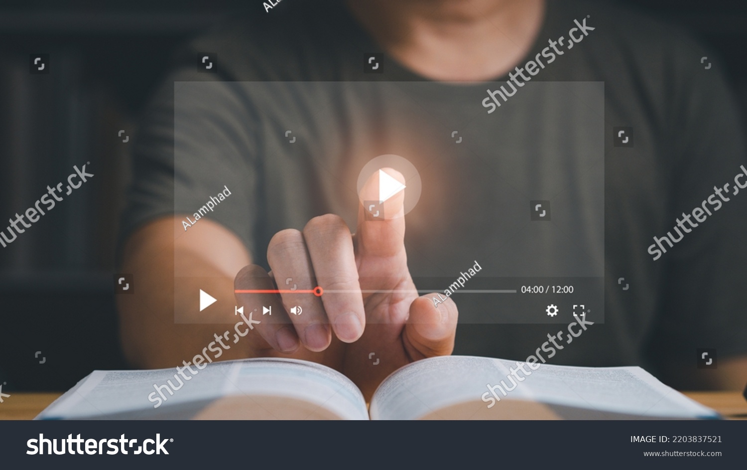 Businessman or student playing the video for learning new technology or music. Finger pointing at play button on virtual screen and a book is on the table. Studying or learning concept. #2203837521