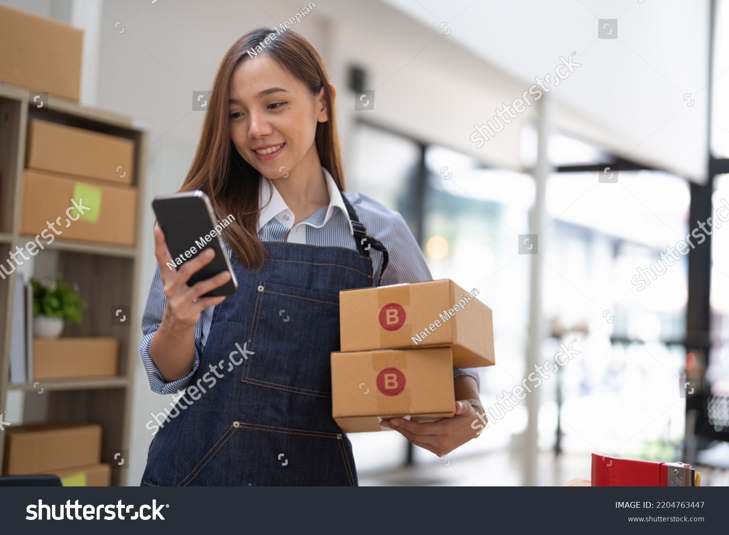 small stock business owner holding phone and retail package parcel boxes checking commercial shipping delivery order on smartphone using mobile app technology. #2204763447