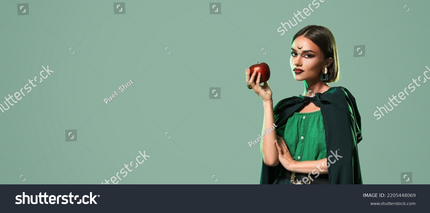 Beautiful woman with apple dressed as witch for Halloween on green background with space for text #2205448069