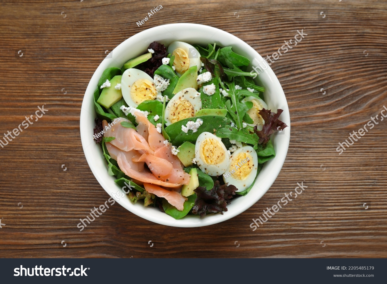 Delicious salad with boiled eggs, salmon and cheese in bowl on wooden table, top view #2205485179