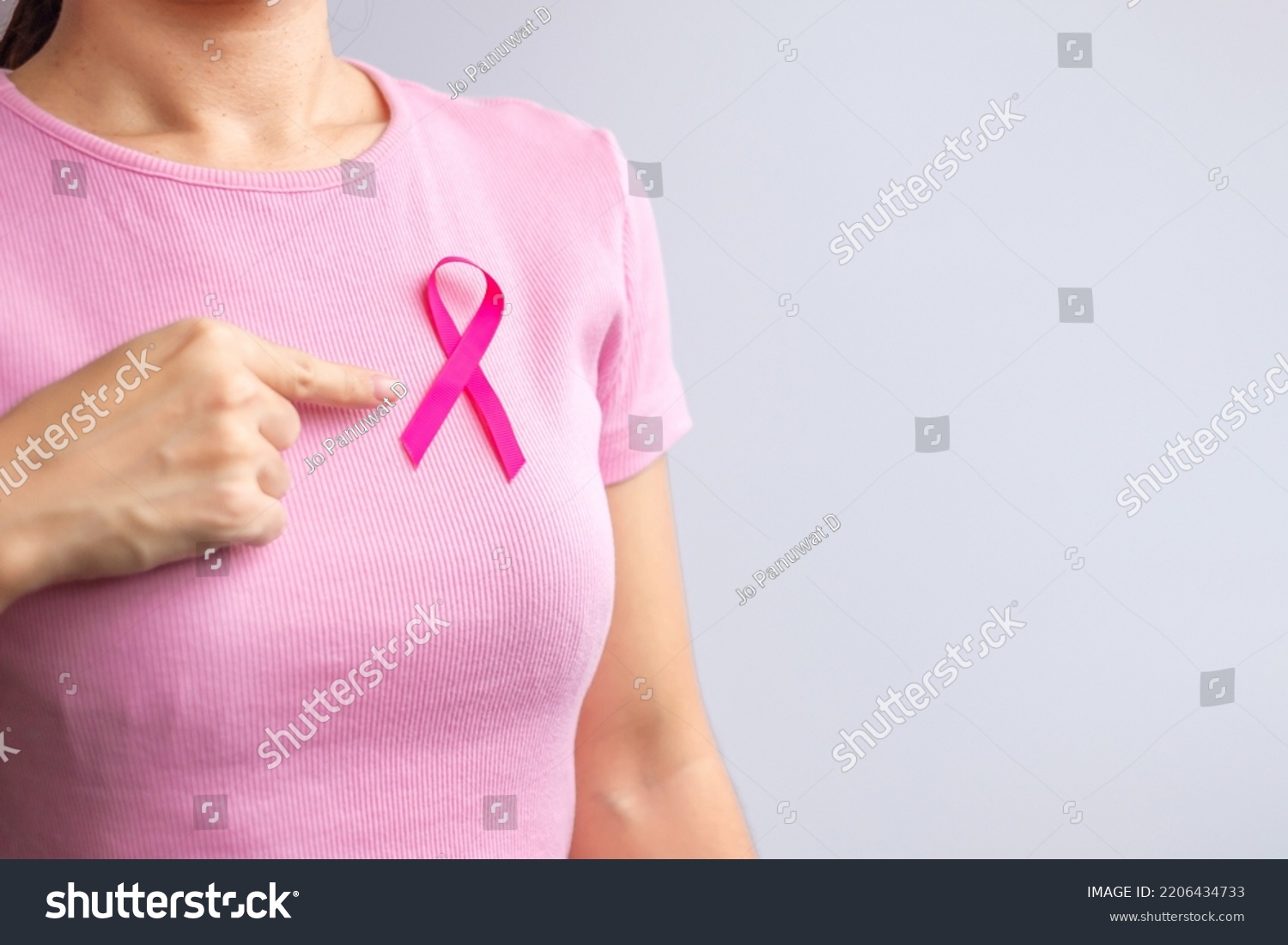 Pink October Breast Cancer Awareness month, woman hand hold pink Ribbon and wear shirt for support people life and illness. National cancer survivors month, Mother and World cancer day concept #2206434733
