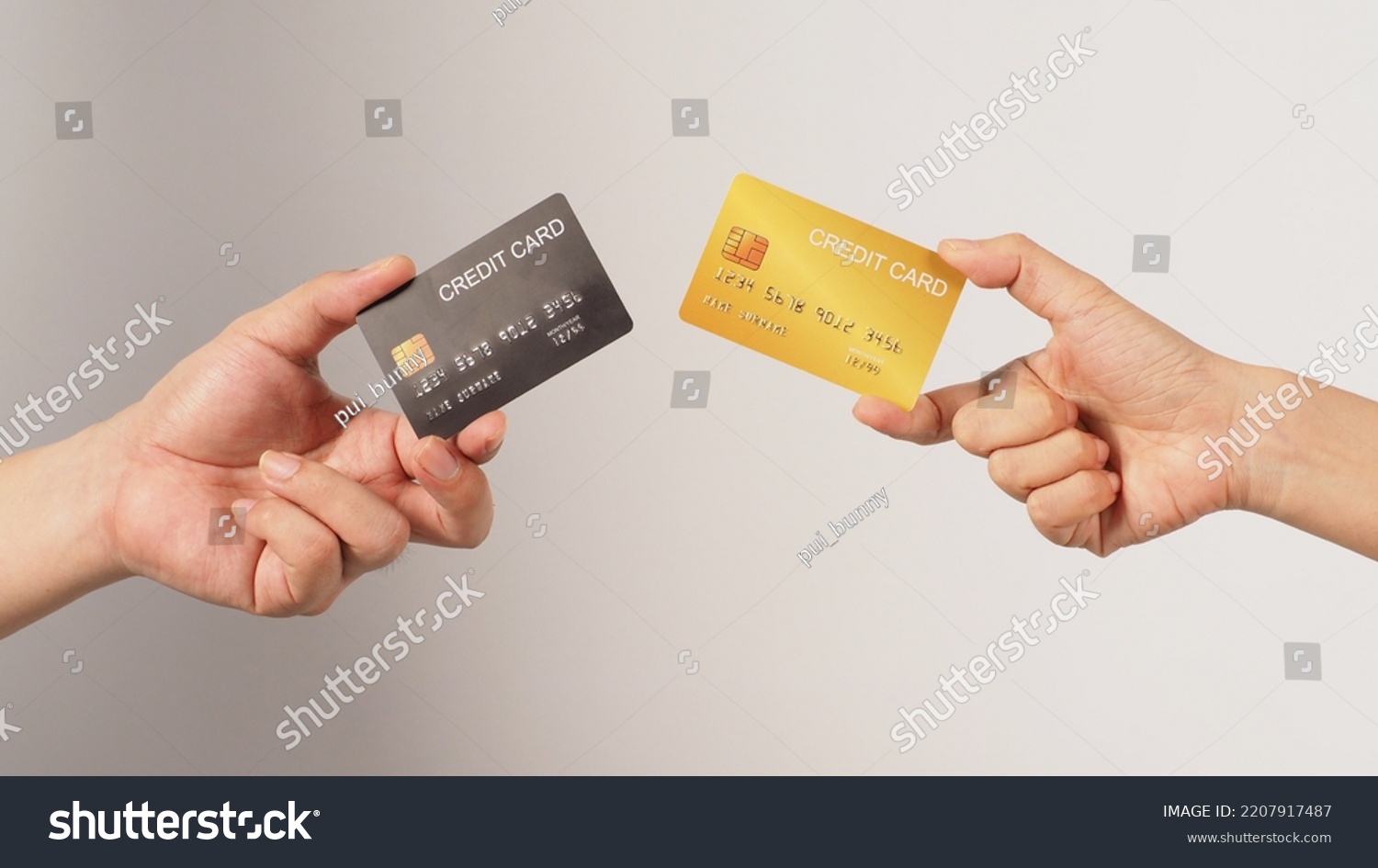 Two hands is hold black and gold credit card on white background.	 #2207917487