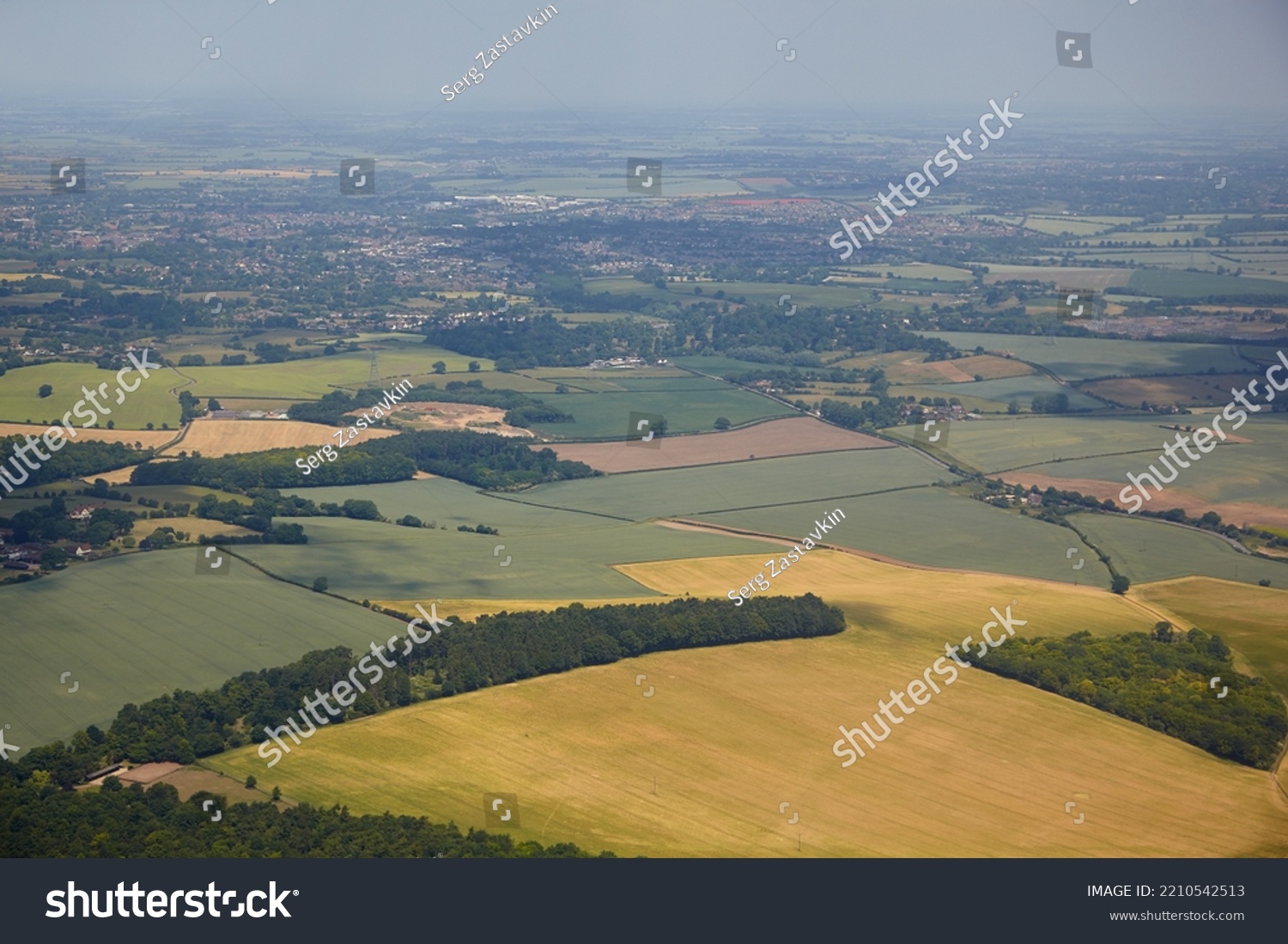 The aerial view of the fields and cousy settlements located in the lowlands surrounding county and university town of Cambridge. Cambridgeshire. United Kingdom #2210542513