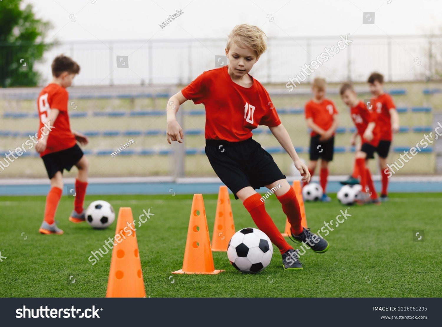 Boys on soccer football training. Young players dribble ball between training cones. Soccer summer training camp. Players on football practice session #2216061295